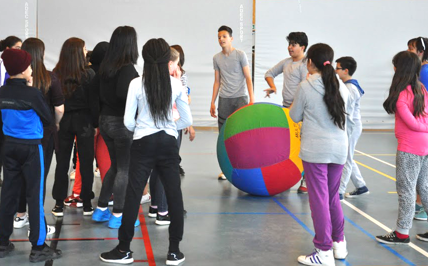 kinderen spelen met een grote bal in een turnzaal